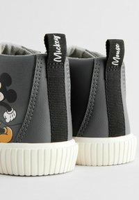 Szare trampki za kostkę z gumową podeszwą, z czarnymi elastycznymi uchwytami i kolorowym wzorem Myszki Mickey na boku.