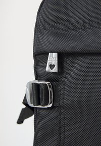 Black textured backpack with a silver buckle and a metal tag featuring "LOVE MOSCHINO" and a heart shape.