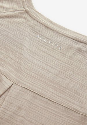 Top de sport beige en tissu lisse et texturé avec un motif rayé subtil. Logo "ACTIVE" imprimé en blanc. Encolure arrondie.