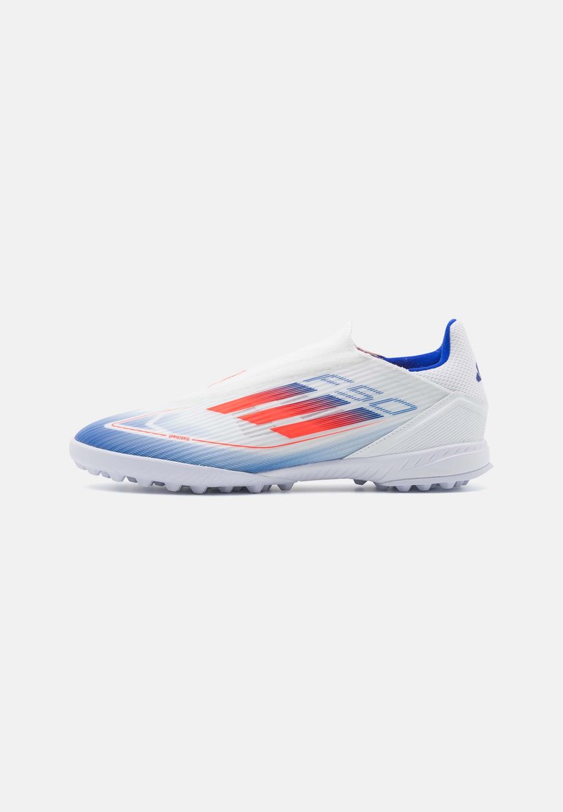 Botín de fútbol blanco con diseño degradado en azul y rojo, franjas rojas, suela texturizada y forro interior azul, mostrado de lado sobre un fondo blanco.