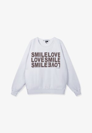 Sudadera blanca con texto en marrón oscuro que repite "SMILE LOVE LOVES SMILE" en orientación apilada y mixta. Cuello redondo, puños acanalados.