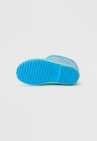 Botte en caoutchouc bleue avec une semelle texturée, ornée de motifs colorés de dauphins. Surface extérieure lisse avec une pointe arrondie et un design à tige basse.