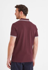 Maroon polo shirt with a classic collar, short sleeves, and white striped accents at the collar and sleeve cuffs. Smooth cotton texture.