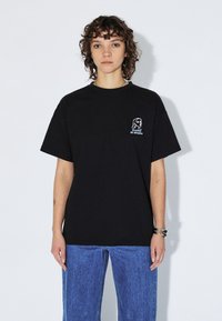 Czarny bawełniany t-shirt z krótkimi rękawami i luźnym krojem. Na przodzie znajduje się biały nadruk z napisem "Dreams of Utopia".