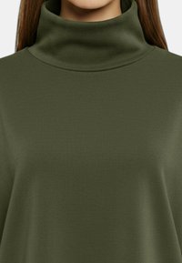 Top dolcevita verde oliva realizzato in morbido tessuto elasticizzato. Presenta un collo alto e una superficie liscia e strutturata. Design minimalista.