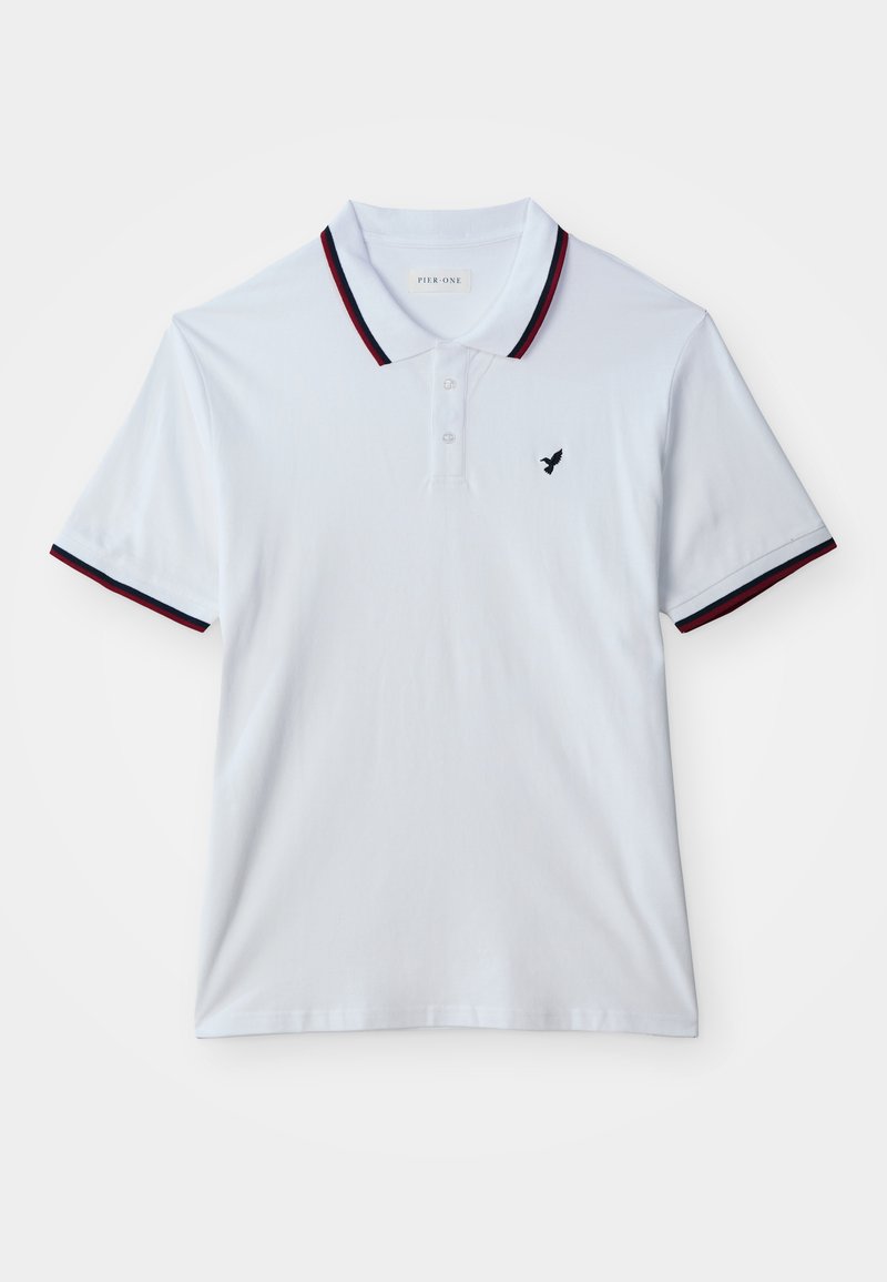 Άσπρο πόλο με κοντά μανίκια, μαύρη και κόκκινη επένδυση στο γιακά και στα μανίκια, τρία κουμπιά και μικρό μαύρο λογότυπο πουλιού στο στήθος.