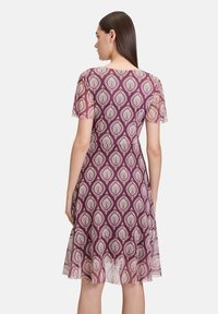 Lila Kleid mit weißem Tröpfchenmuster, kurzen Ärmeln, einem taillierten Oberteil und einem ausgestellten Rock, besteht aus einem weichen, leichten Stoff.