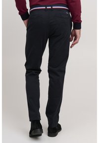 Navy chinos with a textured finish, featuring a multicolored striped waistband and back pockets, paired with black ankle boots.