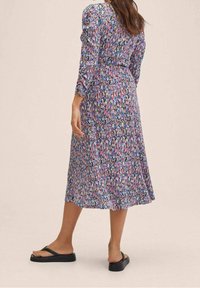 Robe midi à imprimé floral multicolore, avec des manches longues et une taille cintrée. Tissu doux et fluide avec une finition légèrement texturée.