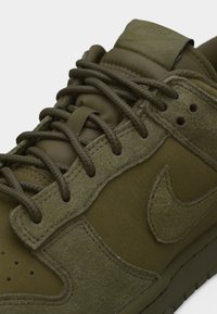 Αθλητικό παπούτσι Nike σε ελιά πράσινο με επενδύσεις από σουέντ, πλεκτά κορδόνια, επενδεδυμένη γλώσσα και κεντημένο λογότυπο Nike στο πλάι.