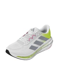 Zapatilla deportiva blanca con rayas grises, acentos rosas y detalles verdes. Presenta una parte superior texturizada y una suela acolchada para mayor soporte.