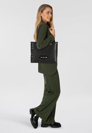Sac fourre-tout noir texturé avec des accents dorés, des détails cloutés et une plaque de logo. Dispose de doubles poignées et d'une forme rectangulaire spacieuse.
