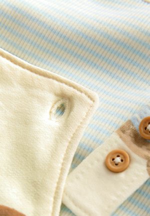 Blue and cream fabric with fine stripes, featuring a beige section and brown buttons. Includes a small hole detail in the fabric.