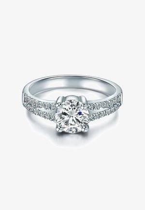 Ezüst eljegyzési gyűrű, középen egy kerek gyémánttal és kisebb kövekkel a szalagon, amely fényes felületével és elegáns kialakításával tűnik ki.