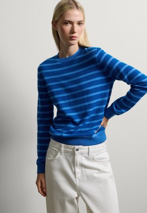 Blauw en lichtblauw gestreept sweater met een ronde hals en geribde manchetten, gecombineerd met witte broeken. Gladde textuur, aansluitend ontwerp.
