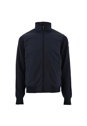 Marineblauwe jas met een hoge kraag, volledige ritssluiting, geribbelde manchetten en een gladde stofstructuur. Heeft zijzakken en contrasterend mouwmateriaal.