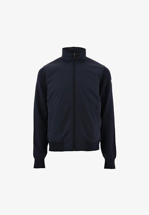 Marineblauwe jas met een hoge kraag, volledige ritssluiting, geribbelde manchetten en een gladde stofstructuur. Heeft zijzakken en contrasterend mouwmateriaal.