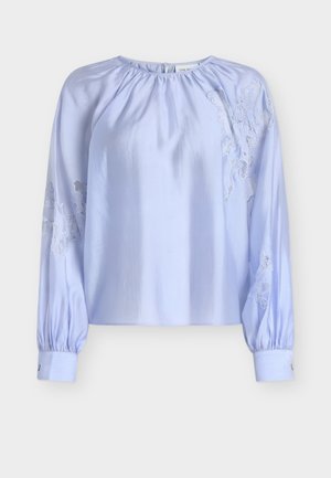 Blouse bleu clair en tissu satin, présentant un col froncé et des manches longues bouffantes avec des accents de broderie en dentelle de chaque côté.