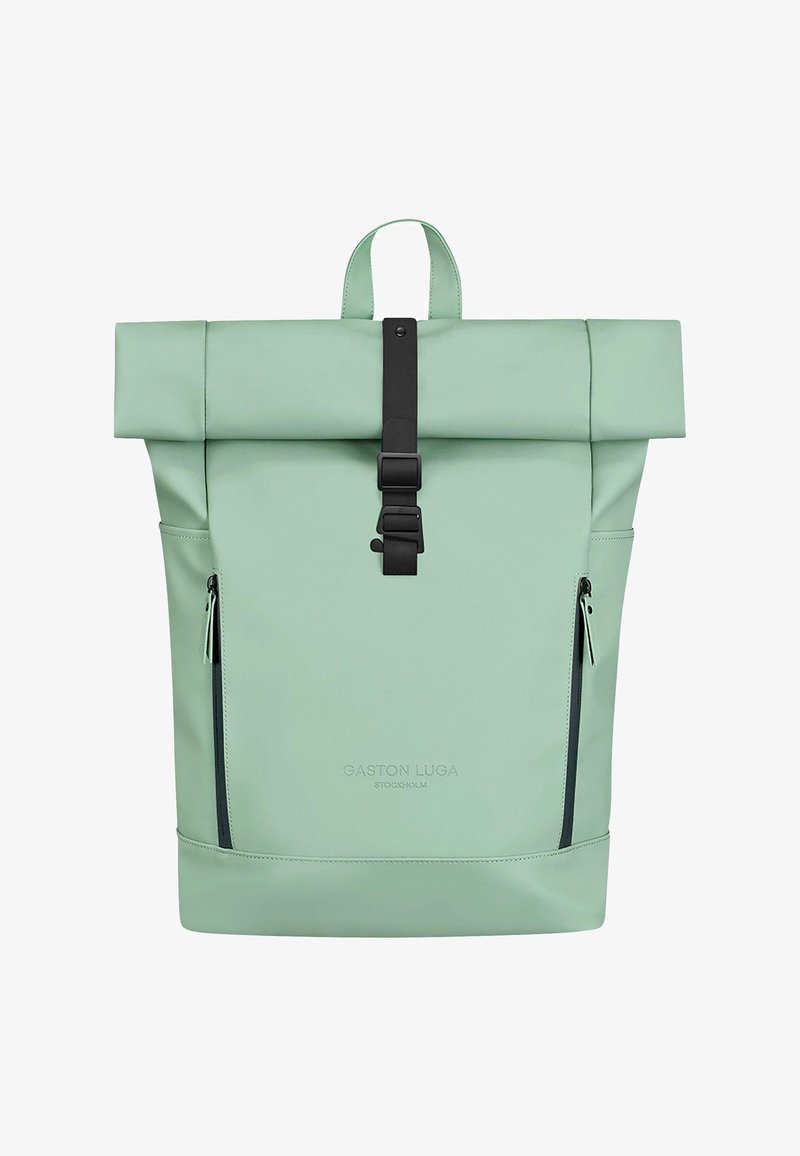 Mochila enrollable de color verde menta con cierre de plástico negro, textura suave, dos bolsillos laterales con cremallera y marca en la base.