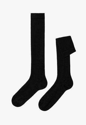 Schwarze kniehohe Socken aus weichem Material, mit glatter Textur und geripptem oberen Rand. Eine Socke ist gefaltet, während die andere aufrecht steht.