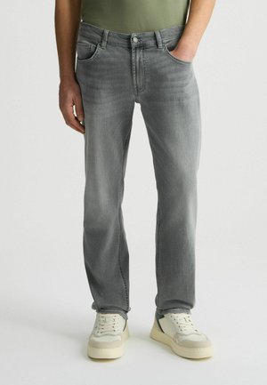Grijze denim jeans met een rechte pijp, vijfzakkenontwerp en een vervaagde afwerking. Draagt een paar sneakers in neutrale kleuren.
