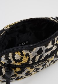 Borsa in tessuto con motivo nero, giallo e grigio, dotata di apertura con zip, presenta un interno foderato e un'etichetta all'interno.