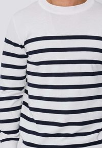 Pull blanc à manches longues avec larges rayures bleu marine, col rond, texture douce et poignets côtelés. Design simple avec motif horizontal.