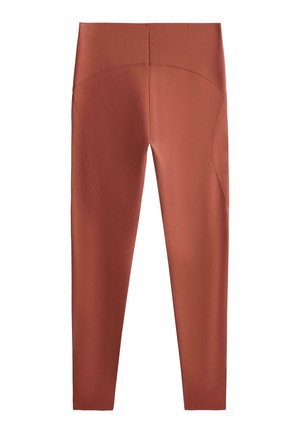 Hoch taillierte Leggings in Rostfarbe mit geschwungenen Nahtdetails an Hüften und Oberschenkeln, glattem Stoff und vollständig zulaufenden Beinen.