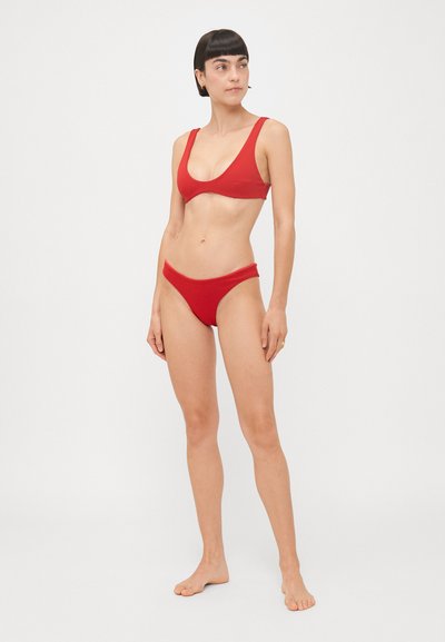 Sarkans bikini komplekts ar izgriezumu apmales, plašām siksnām un saskaņotiem augstiem šortiem ar gludu, matētu apdari.