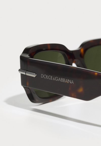 Oversized tortoiseshell sunglasses with green lenses. Features silver hardware accents and engraved logo on the temple.