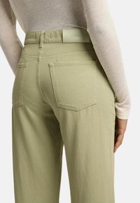 Lichtgroene, hoogwaisted broek met een recht model, voorzien van twee achterzakken en een subtiele logo patch op de tailleband.