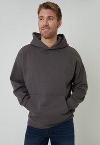 Mørkegrå hættetrøje lavet af blødt, tykt stof med en frontlomme og justerbar snøre. Afslappet pasform med ribbede manchetter og kant.