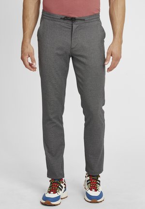Grå mønstrede bukser med snor i taljen, slim fit og sidelommer, parret med farverige træningssko med iøjnefaldende accenter.