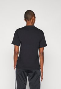 Svart kortärmad T-shirt med rund hals, gjord av mjuk bomull, med en slät textur och en tight passform.