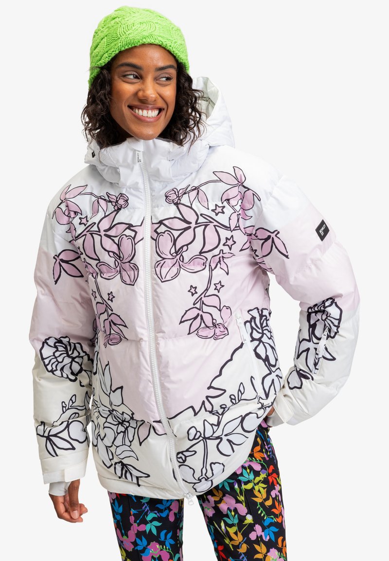Polstret hvid jakke med pink blomsterprint og sorte kanter, med lynlås foran og hætte. Parret med farverige mønstrede leggings.
