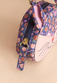 Rund väska med blommönster i blått och rosa, med dragkedja och guldiga detaljer samt söta kattöron på toppen.