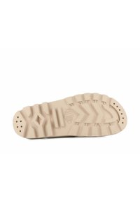 Beige kumiristikkipesän pohja, jossa on teksturoitu pito kuvioita, mukaan lukien siksak- ja ympyrämuotoisia kuvioita. Yksityiskohtia ovat ilmanvaihtoaukot ja brändäys.