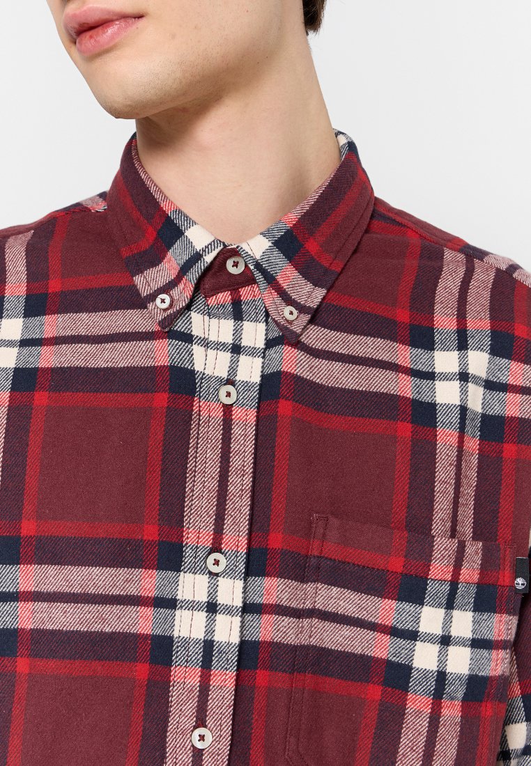Camicia a quadri rossa e blu in cotone, con colletto, taschino sul petto e motivi a scacchi bianchi e blu a contrasto.