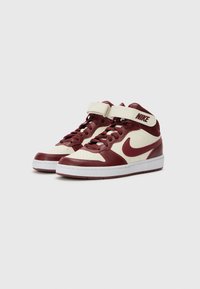 Visoke teniske sa gornjim dijelom od maroon kože, kremastu dekoraciju i bijeli potplat. Ima vezice i trakicu s Nike logom.