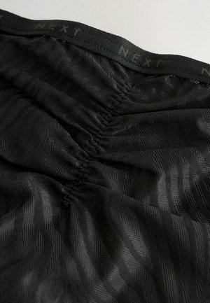 Tessuto a rete nero con motivo a strisce zebrate e vita elastica arricciata con il marchio "NEXT" lungo il bordo superiore.