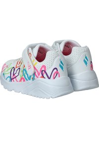Zapatillas blancas con patrones de corazones coloridos, con una cinta de Velcro, detalles perforados y una suela de goma texturizada.