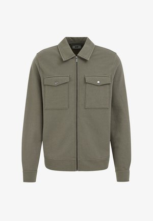 Olivgrüne Jacke aus weichem Stoff, mit einem Reißverschluss vorne, spitzem Kragen und zwei Brusttaschen mit silbernen Druckknöpfen.