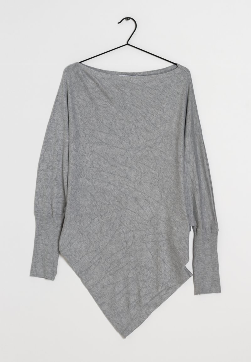 Haut gris à manches longues en tissu doux avec un ourlet diagonal. Il présente un col large et une coupe décontractée avec un détail texturé.