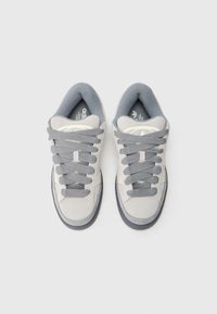 Šedé tenisky s vrchní částí z broušené kůže a textilu, světle šedými tkaničkami, kulatou špičkou, polstrovaným jazykem a gumovou podrážkou. Výrazné logo se třemi pruhy.