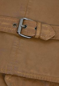 Hellbrauner Ledergürtel mit einer Metallschnalle, versehen mit Steppdetails und einer spitzen Enden. Glatte Textur, mit einem schlichten Design.