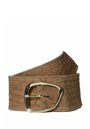 Ceinture en cuir marron texturé avec une grande boucle métallique argentée brillante et asymétrique, enroulée sur un fond blanc.