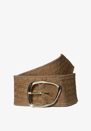 Ceinture en cuir marron texturé avec une grande boucle métallique argentée brillante et asymétrique, enroulée sur un fond blanc.