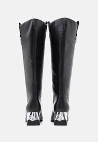 Mustast nahast põlvikud, millel on stiilne disain, esitledes läikivaid hõbedasi aktsente plokk-kantidel ja dekoratiivseid silmuseid ülaosas.