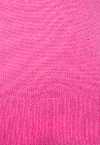 Maglione rosa lavorato a maglia con una texture liscia e orlo a coste. Il design è semplice con un colore uniforme in tutto il capo.