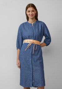 Jeanskleid mit taillierter Silhouette, dreiviertelärmel, durchgehender Knopfleiste und einem hellbeigen Ledergürtel, der an der Taille gebunden ist.